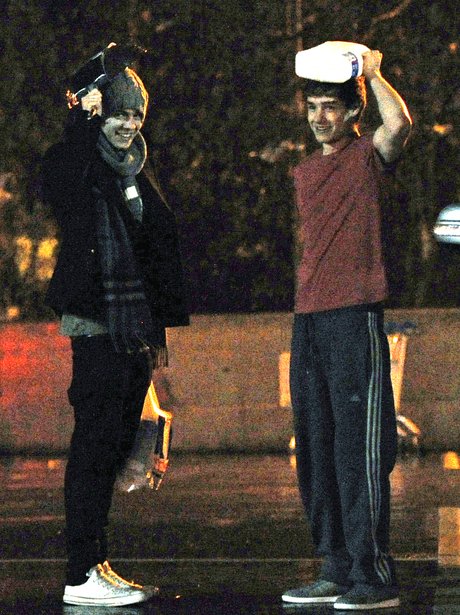 Harry and Liam form One Direction shelter from rain.