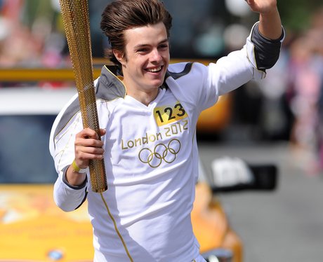 A happy torchbearer holding the Olympic flame
