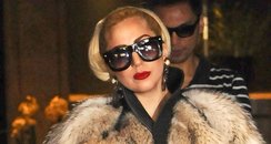 Lady Gaga wears a fur coat while carrying her dog