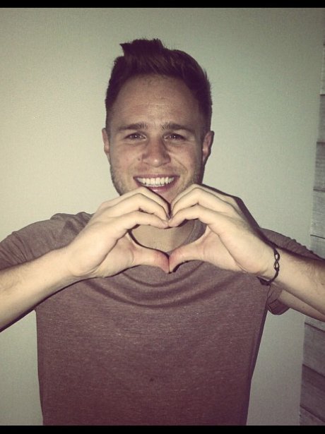 Olly Murs holds his hands in a heart symbol