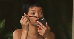 Rihanna wearing stripey dress applying make up