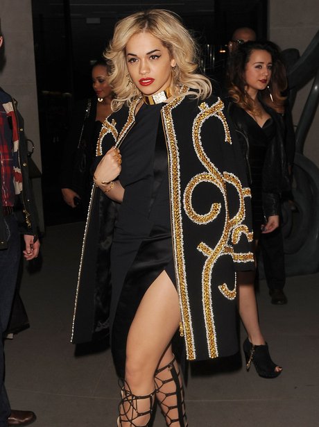 Rita Ora wearing a gold and black jacket at London Fashion Week 2013