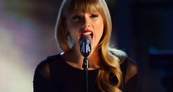 Taylor Swift performs onstage in tight black dress