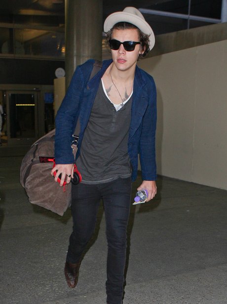 Harry Styles arrives at LAX wearing a hat