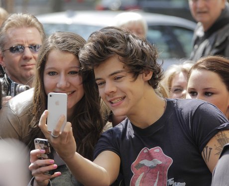 Harry Styles taking picture of himself with a fan's camera phone