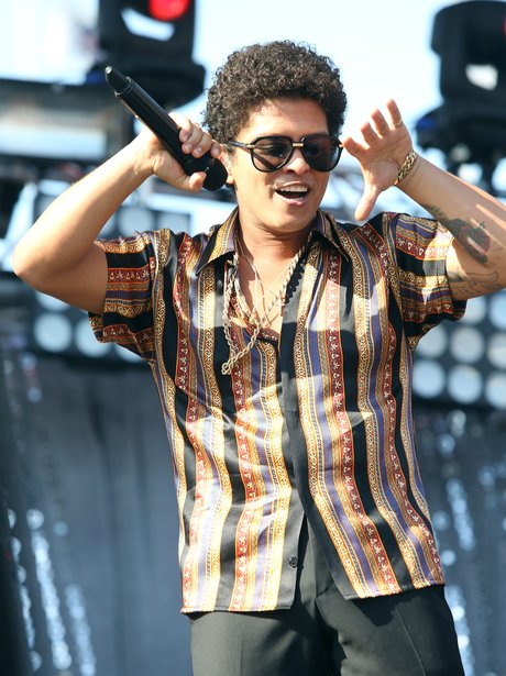 Bruno Mars wearing a stripey shirt on stage