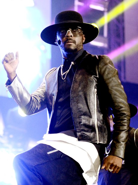 Will.i.am on stage holdijng his arm in the air