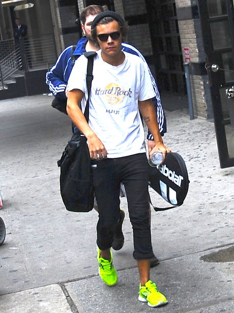 Harry Styles carries his tennis racket