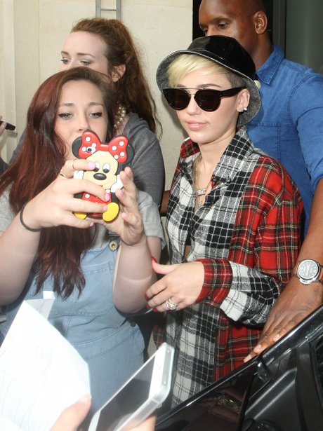 Miley Cyrus poses for a picture with a fan using a Minnie Mouse camera