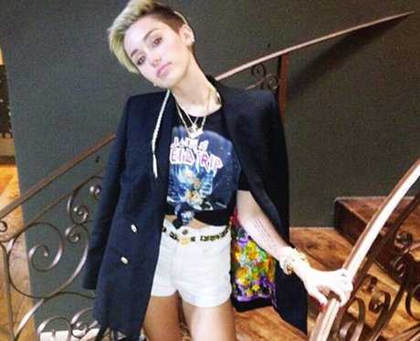 Miley Cyrus standing on a staircase in white hot pants