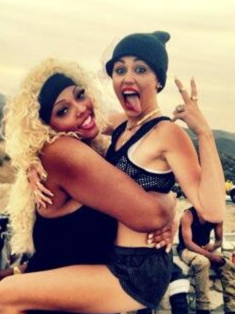 Miley Cyrus with her tongue out while being carried by a friend