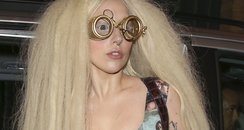 Lady Gaga carrying a guitar and wearing glasses