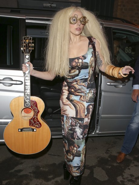 Lady Gaga carrying a guitar and wearing glasses