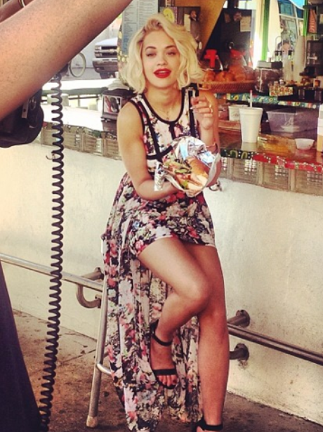 Rita Ora eating a burger on photoshoot set