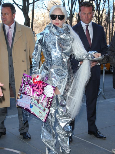 Lady Gaga wearing a foil outfit carrying a birthda