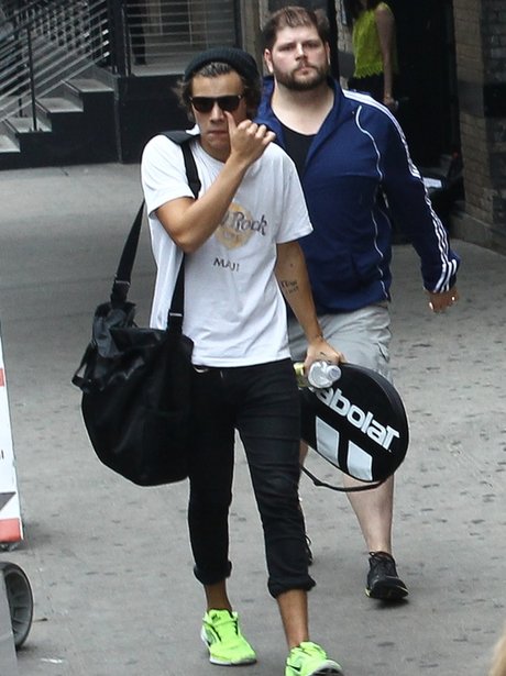 Harry Styles carrying a tennis racket