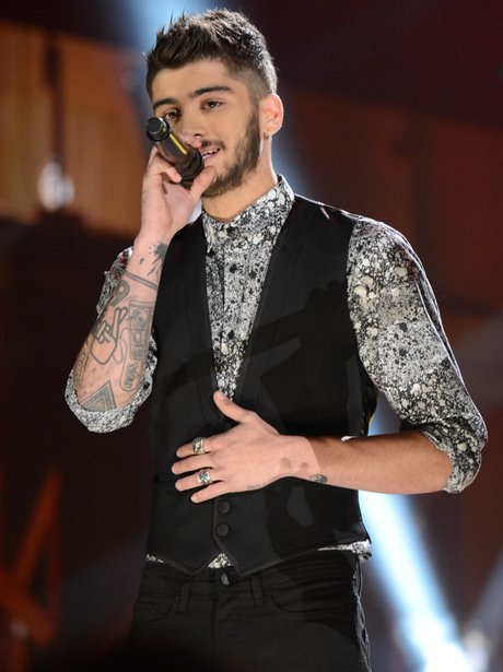 Zayn Malik performing on stage in a waistcoat 