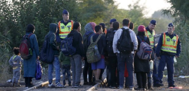 Police stopping Syrian refugees on a railway line