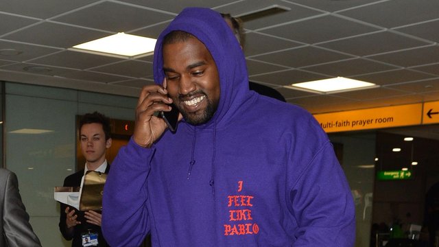 Kanye West shares a rare smile at London Heathrow