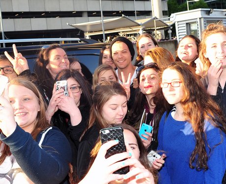 Louis Tomlinson poses with a group of female fans