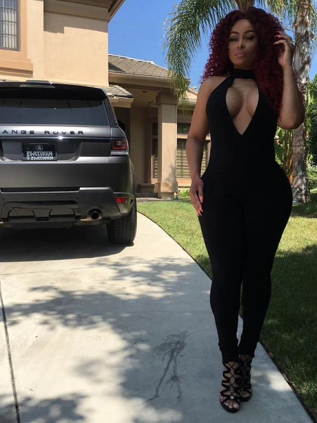 Blac Chyna poses in plunging black jumpsuit outsid