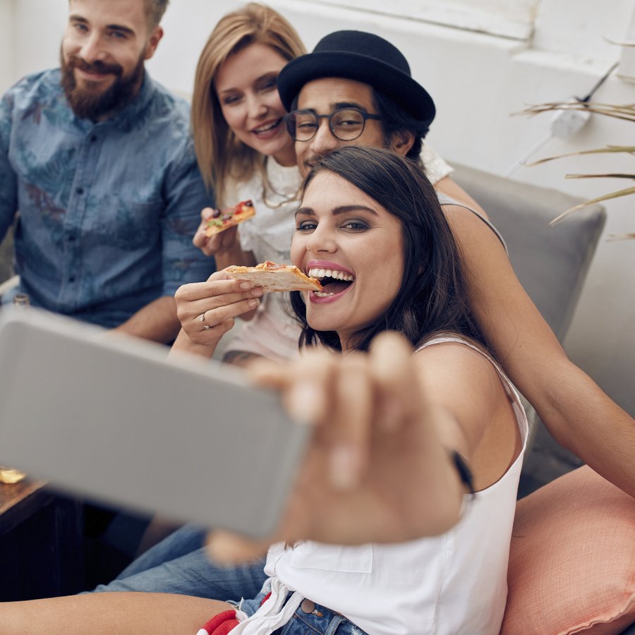 Young people taking a selfie while eating pizza