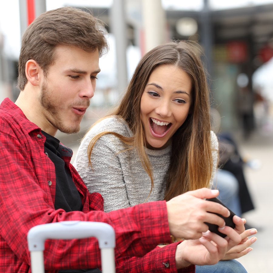 Couple playing games with a smart phone in train station