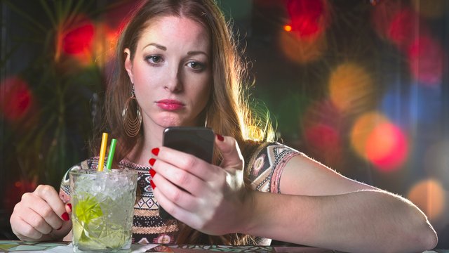 Disappointed woman looks at her mobile phone