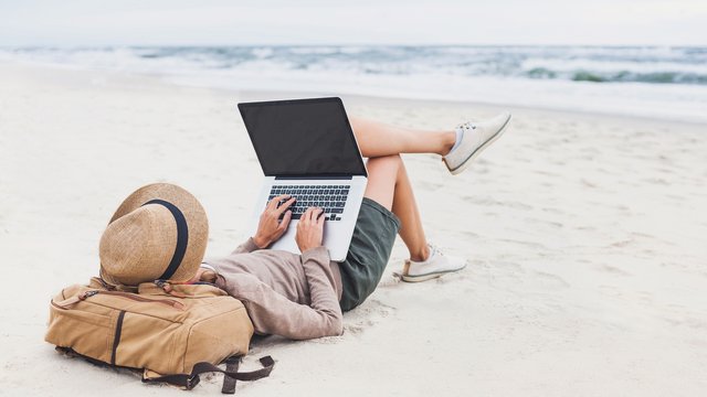 person on laptop on the beach